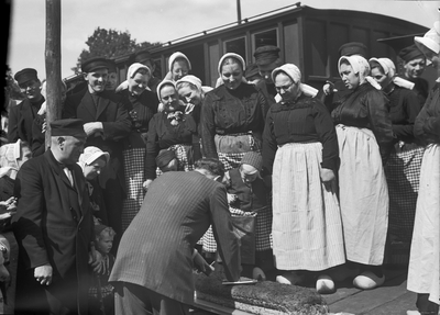 167312 Afbeelding van het snijden van een krentenwegge bij een groepje personen in Twentse klederdracht, tijdens een ...